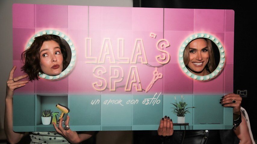 Isabella Santiago sourit à travers une découpe colorée du logo Lala’s Spa.