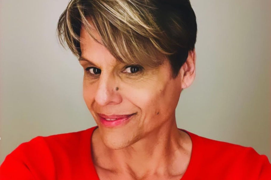 Alexandra Billings with a fresh haircut in Times Square, wearing a red top and smiling.