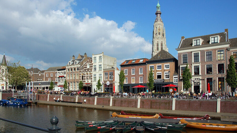 Bateaux amarrés au port de Breda avec bâtiments anciens et la tour de la Grote Kerk en arrière-plan.