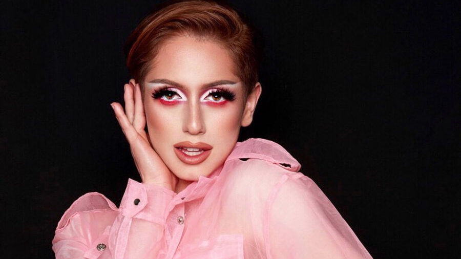 Brendan Jordan wearing a sheer pink shirt and black corset against a black backdrop.
