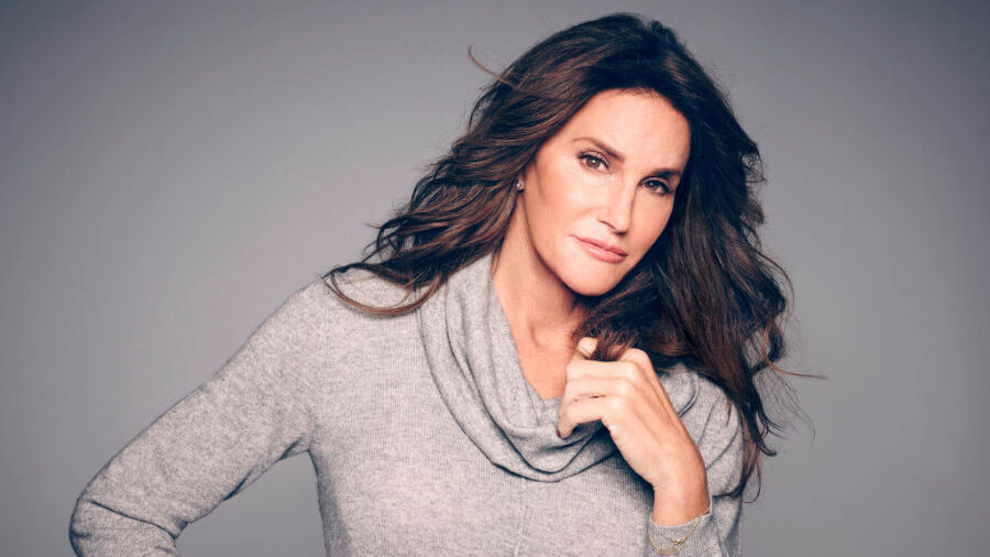 Caitlyn Jenner dans une pose calme, la main près du col, les cheveux coiffés, devant un fond neutre.