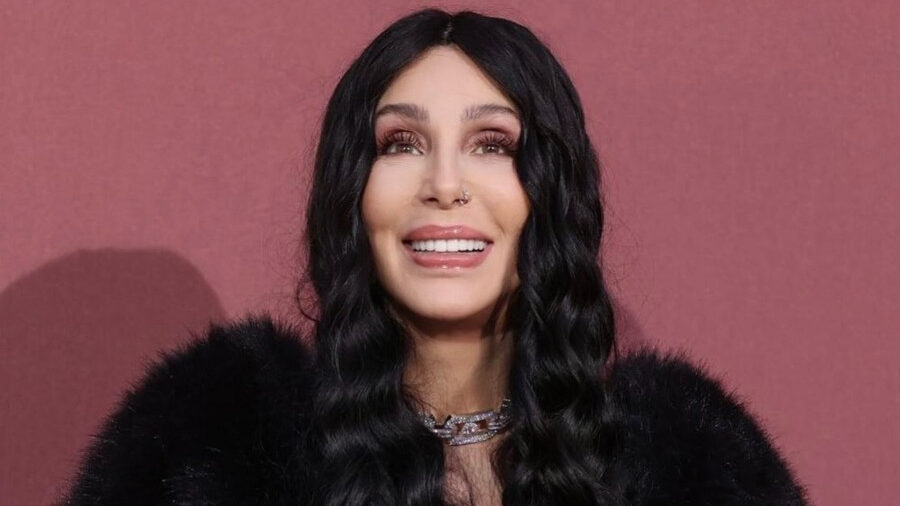 Singer Cher poses in Cannes, wearing a voluminous black fur coat, fingerless gloves, and a diamond necklace.