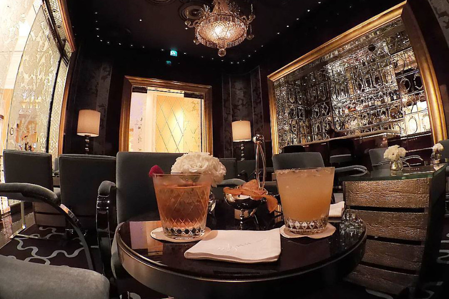 Two cocktails on a table at Bar Cristal, inside Wynn Macau, with mirrored walls and chandelier in view.