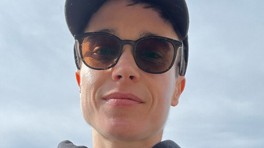 Selfie of Elliot Page outdoors in a cap, hoodie, and chest strap.