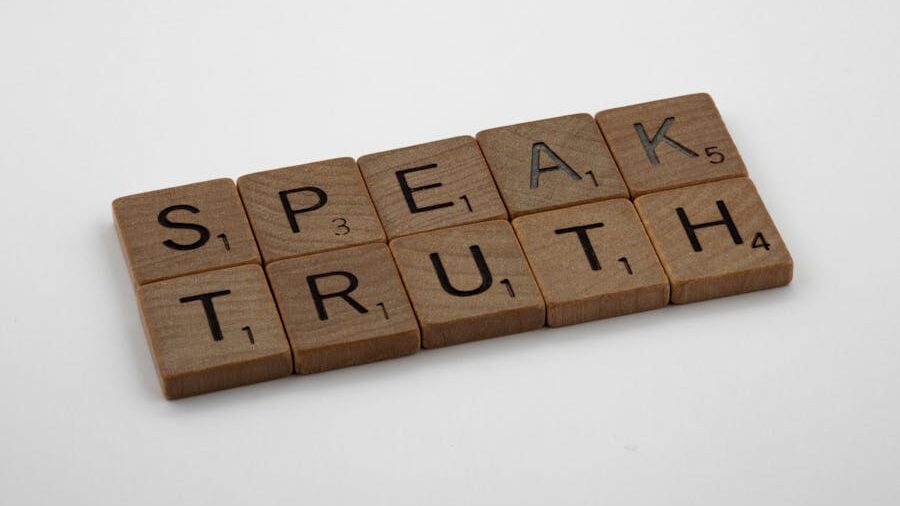 Wooden Scrabble-style tiles arranged on a white surface spelling out the words “Speak Truth” in capital letters.
