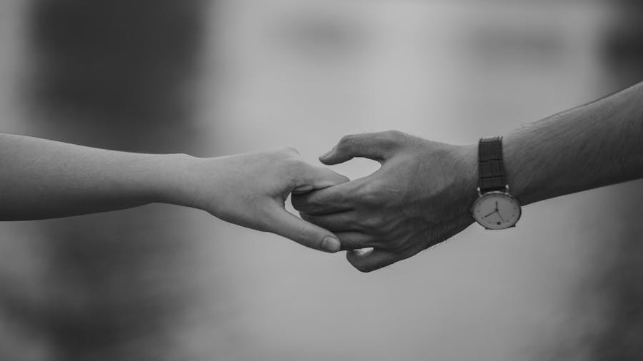 Black and white image of two hands gently holding each other, symbolizing connection and affection.