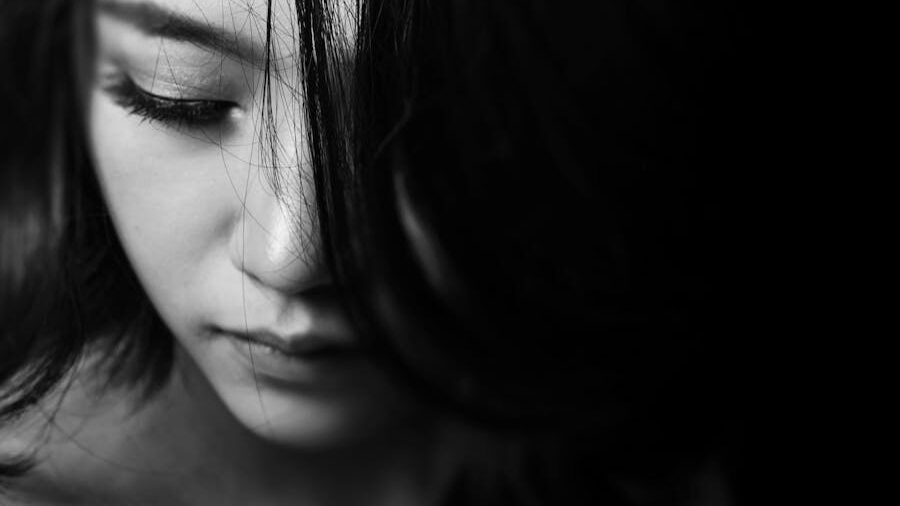 Primer plano en blanco y negro de una mujer con rasgos suaves que mira hacia abajo pensativamente.