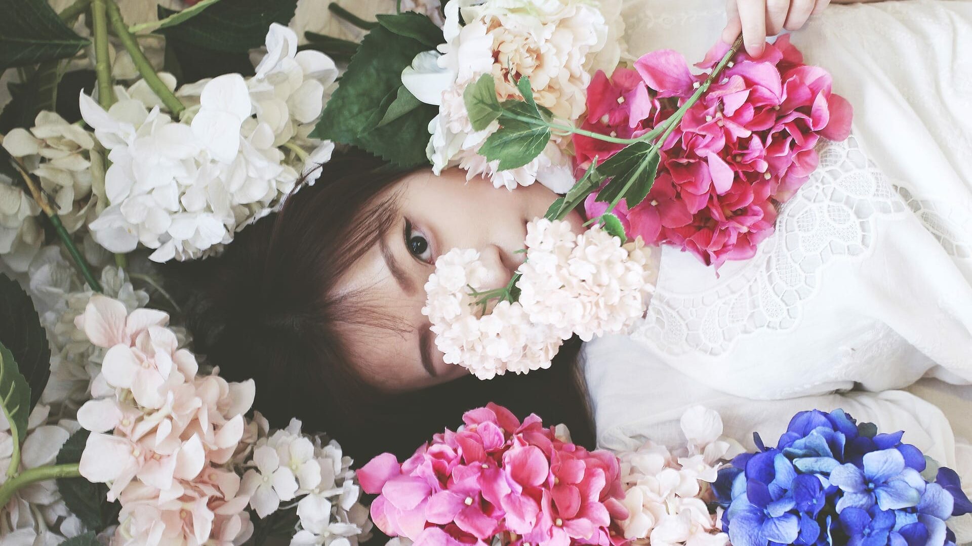 Femme allongée parmi des fleurs colorées avec seulement ses yeux visibles