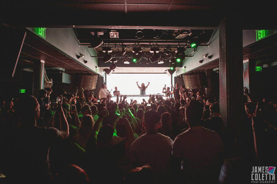 A crowded night at ICON Nightclub in Boston with people dancing and a DJ performing on a lit stage.