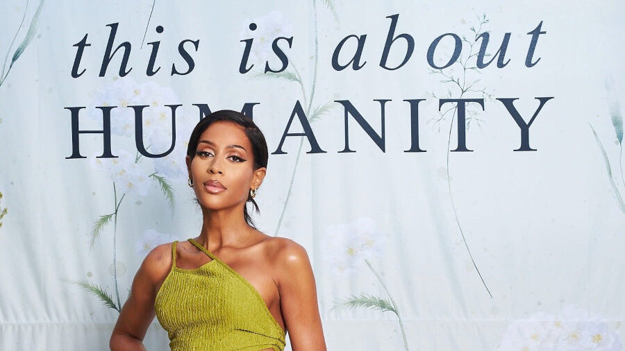 Isis King poses in a green asymmetrical dress in front of a backdrop reading “This Is About Humanity,” August 2025.