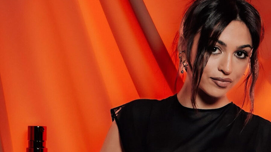 Fashion shot of Josie Totah in black mesh dress next to Divine perfume bottle, Jean Paul Gaultier.