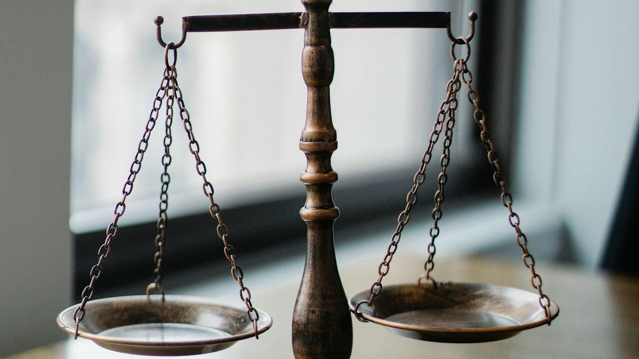 Balanced antique brass scales with shallow bowls, placed indoors near a window.