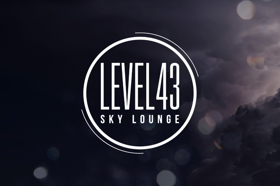 White circular logo of Level 43 Sky Lounge on a dark sky background with clouds and blurred light reflections.