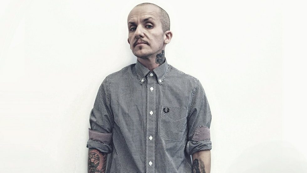 Lucas Silveira stands against a white wall in a Fred Perry shirt for Anchor Campaign.