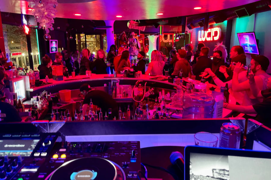 Inside Lucid Bar with a full circular bar, colorful lighting, and people enjoying drag and drinks.