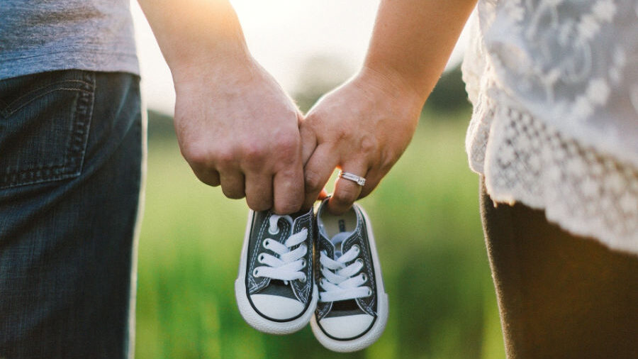 Dos personas sosteniendo zapatos de bebé juntos.