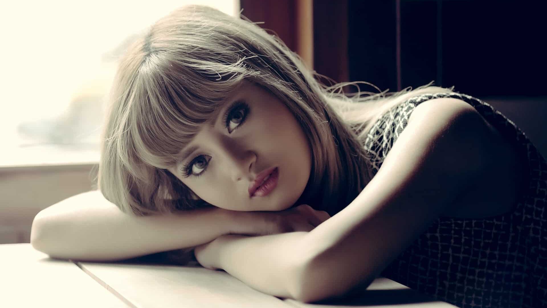 Femme reposant sa tête sur ses bras, regardant pensivement vers la caméra.