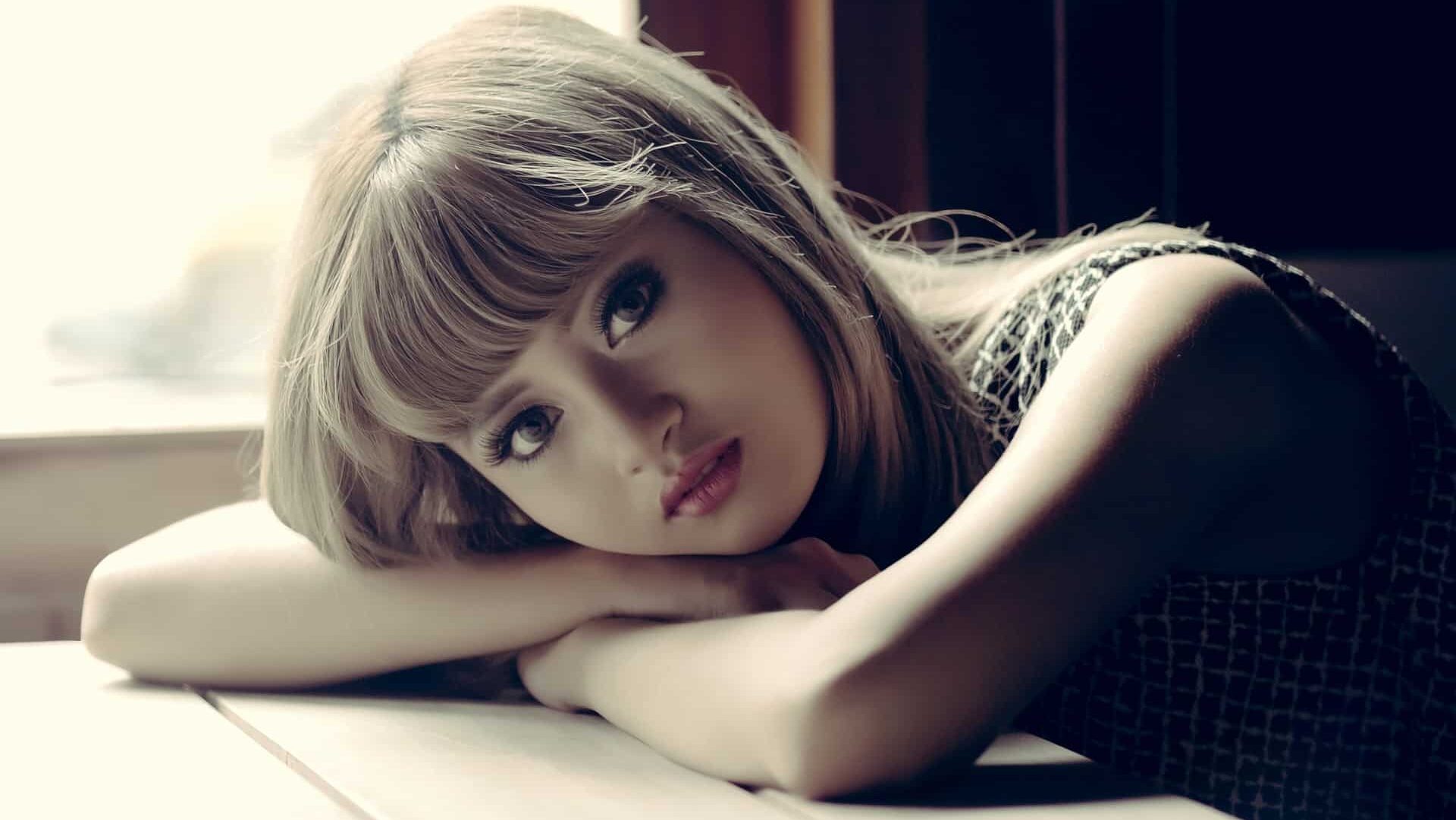 Woman resting her head on her arms, gazing thoughtfully towards the camera.