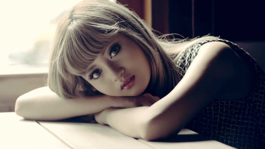 Mujer apoyando su cabeza en los brazos, mirando pensativamente hacia la cámara.