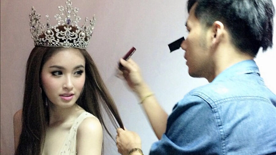 Nong Poy wearing a jeweled crown, having her hair styled by Tom Surat during a glam session.