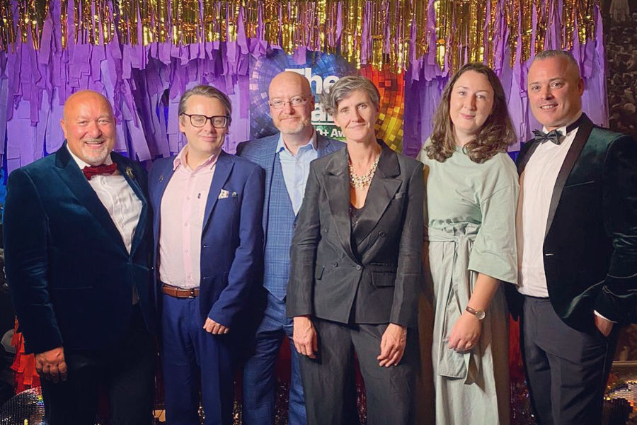 Board members of NXF posing in front of The Galas 2023 backdrop with gold and purple decorations in Dublin.