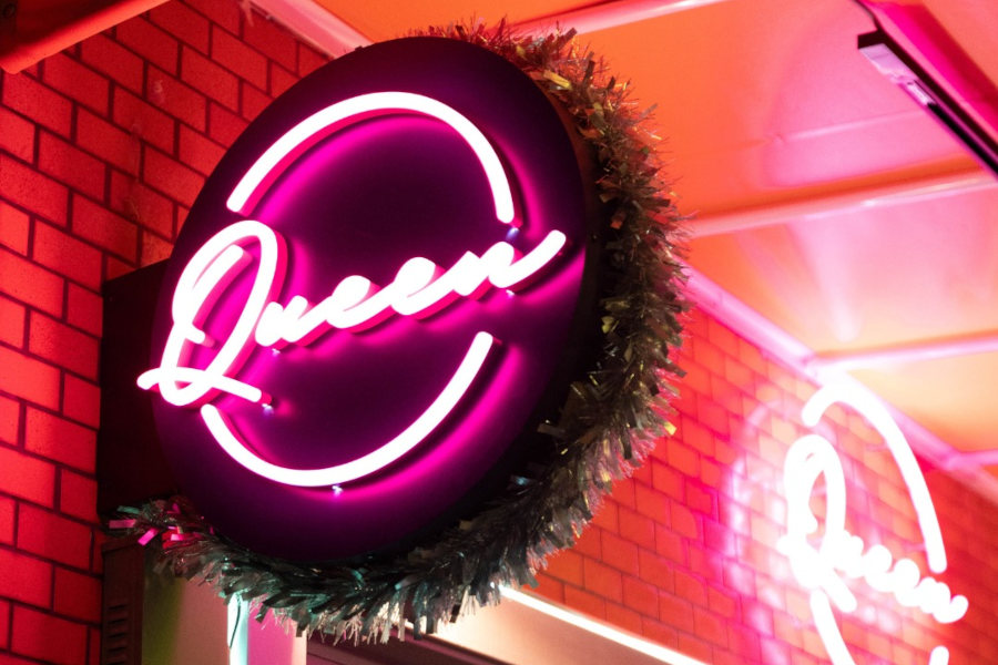 Neon sign reading “Queen” mounted above the entrance of Queen Tokyo Bar, photographed at night.