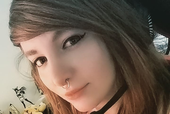 Close-up of Remilia, pro gamer and NA LCS pioneer, posing with a headset and light makeup at her desk.