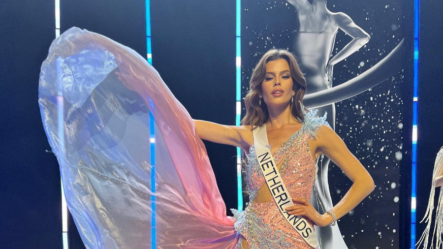 Rikkie Kollé in a pink-blue-white gown posing proudly on stage at Miss Universe 2023 in El Salvador.
