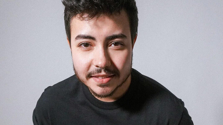 Leo Sheng sonriendo a cámara con camiseta negra “Vote Trans”.