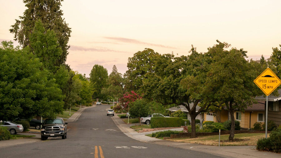 Vue d’une rue de quartier à Sacramento bordée d’arbres et de maisons, capturée à la tombée du jour.