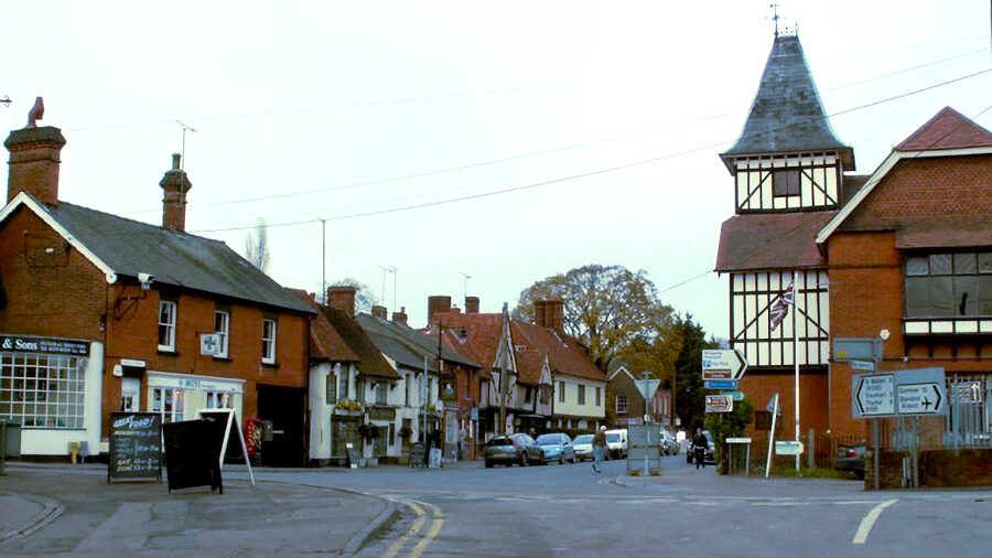 Vue de Lower Street à Stansted Mountfitchet, Essex, avec bâtiments traditionnels et panneaux routiers.