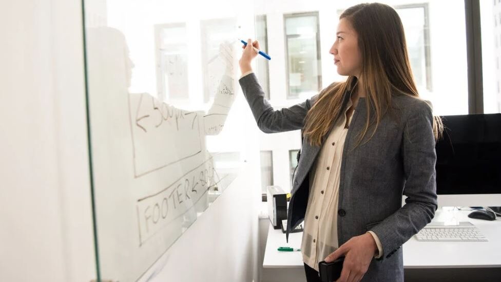 une femme trans écrit sur un tableau