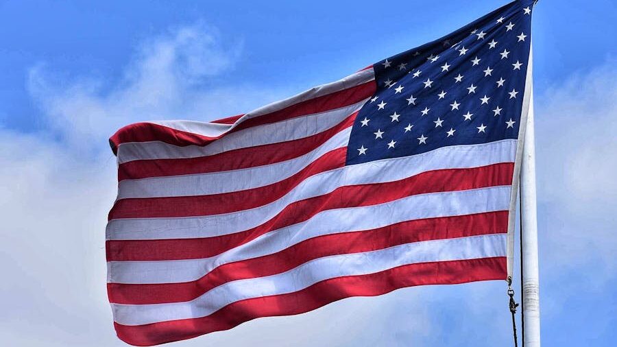 La bandera de los Estados Unidos ondea contra un cielo celeste.