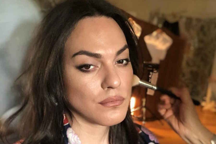 Primer plano de Daniela Vega mientras le aplican maquillaje, con una bata estampada, durante los preparativos para un evento en Santiago.