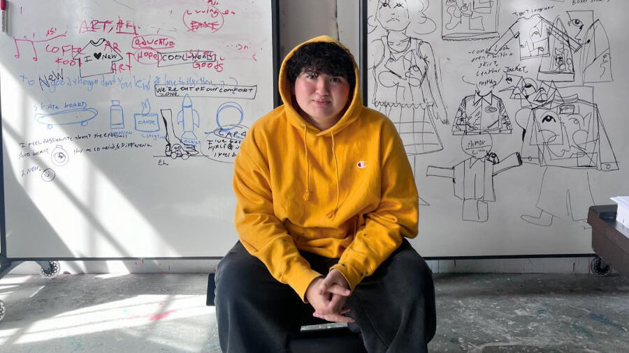 Victor Langlois sentado frente a dos pizarras con bocetos y anotaciones.