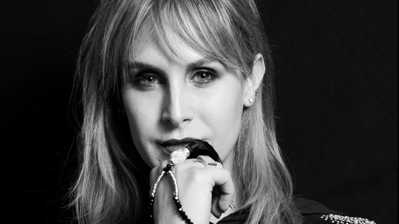 Zackary Drucker stares at the camera in a black and white portrait, wearing a black top with beaded shoulder detailing.